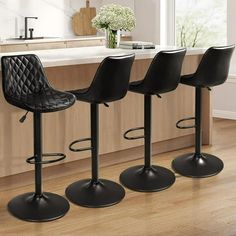 three black bar stools sitting on top of a wooden floor next to a counter