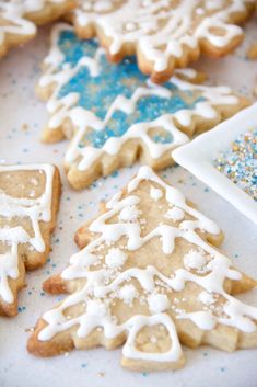 several decorated cookies on a table with blue sprinkles and white frosting