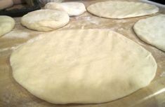 several uncooked pizza doughs sitting on top of a table