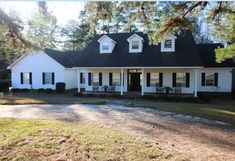 a white house with black shutters on the front and side windows is shown in this image