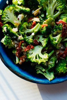 a blue bowl filled with broccoli on top of a table