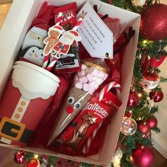 a box filled with candy and candies next to a christmas tree