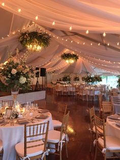 the inside of a tent with tables and chairs set up for a formal function at night