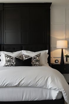 a bed with white sheets and black headboard in a bedroom area next to two lamps