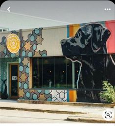 a large black dog is painted on the side of a building with colorful tiles and geometric designs