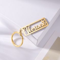 a gold keychain with the word wanna on it sitting on top of a white box