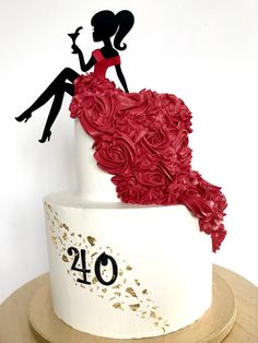 a white cake decorated with red flowers and silhouettes of two people sitting on top