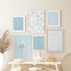 a white table topped with pictures and vases filled with flowers next to a wall