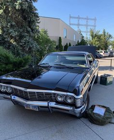 an old black car is parked on the sidewalk