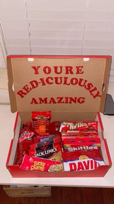 an open box filled with candy sitting on top of a white counter next to a sign that says you're ridiculous amazing