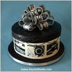 a black and white cake with silver decorations on it's top, sitting on a blue surface