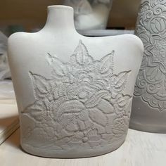 two white vases sitting next to each other on a table