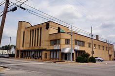 an old building on the corner of a street with power lines above it and cars parked in front