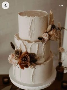 a three tiered wedding cake with feathers and flowers