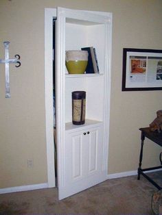 a white book shelf with some books on it in a living room next to a door