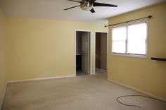 an empty room with a ceiling fan and yellow walls