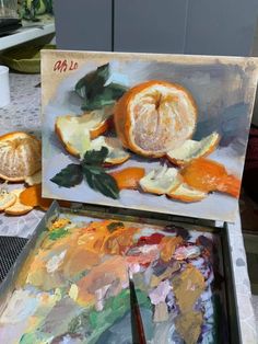 an artist's easel with oranges on it and other art supplies in the background