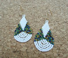 two white and green beaded earrings sitting on the ground