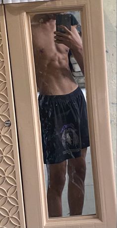 a shirtless man taking a selfie in front of a mirror