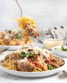 a fork full of pasta with meat sauce and parmesan cheese on the side