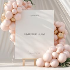 a welcome sign surrounded by balloons and greenery with a white sheet on the front