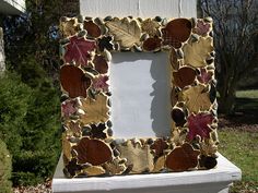 an old photo frame with leaves on it is sitting in the grass next to a house