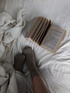 a person laying in bed with their feet on an open book