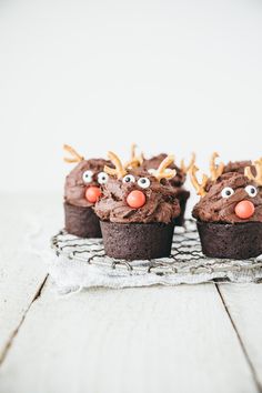 three cupcakes decorated like reindeer faces on a wire rack