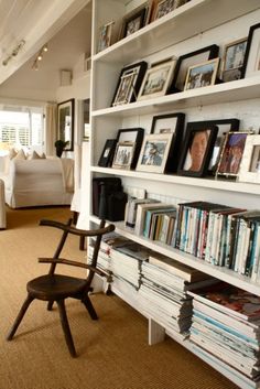 a room filled with lots of books and pictures on the wall next to a chair