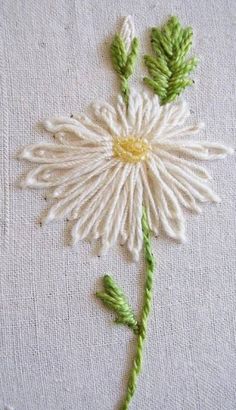 a close up of a flower on a piece of cloth with green thread and needles