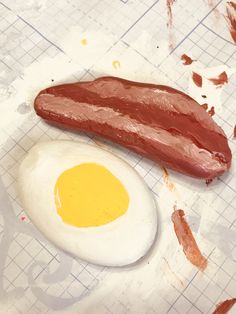 an egg and sausage are on a cutting board next to some brown paint splatters