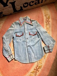 This is one amazing find! Light wash denim  snap shirt Rad Santa Fe Native American chiefs head image on back with sequin stitching on back on cuffs of sleeves and along collar and chest pockets Flap chest pockets with snap closures This is truly a unique piece There are several smaller rust stains on this shirt Through out the shirt Photos taken reveal the staining Tag reads size small Measurements are approximate and taken flat so please double bust and waist for more accurate sizing Bust: 16 Vintage Medium Wash Top With Button Closure, Fitted Medium Wash Shirt For Fall, Medium Wash Fitted Western Tops, Vintage Medium Wash Top With Buttons, Retro Fitted Denim Tops, Vintage Denim Button-up Top, Retro Button-up Denim Top, Retro Denim Button-up Top, Vintage Medium Wash Pre-washed Tops