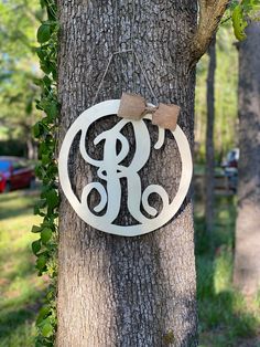 a metal monogrammed ornament hanging on a tree with a bow around it