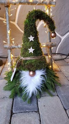 a gnome's hat made out of moss with lights on the side and white feathers