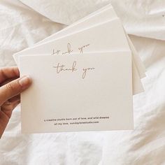 someone holding up two thank cards with writing on them