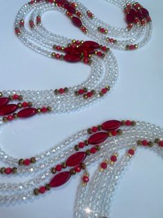 Why You'll Love It: Iridescent Shine: Clear crystal glass beads catch the light beautifully, adding a dazzling touch to any outfit. Red and Gold Accents: Premium red and gold seed beads create a striking contrast, enhancing the overall elegance. Adjustable Fit: Designed to fit comfortably and securely on any body type. Cultural Elegance: A perfect blend of Ivorian tradition and modern sophistication. Versatile Style: Perfect for special occasions, casual outings, or simply adding a touch of sparkle to your everyday wear. This waist bead can be worn alone or layered with other pieces for a unique and personalized look. Description: Introducing the Abure Iridescent Crystal Glass Waist Bead, a handcrafted masterpiece by skilled artisans. The clear iridescent beads create a mesmerizing effect, Red Crystal Beaded Necklaces For Party, Red Crystal Beaded Necklace For Party, Red Faceted Beads Necklace For Party, Red Party Beaded Necklaces With Gold Beads, Elegant Red Beaded Necklace For Christmas, Red Crystal Beaded Necklaces With Round Beads, Red Crystal Beaded Necklace With Round Beads, Party Beaded Glass Crystal Necklaces, Elegant Red Crystal Beaded Necklaces