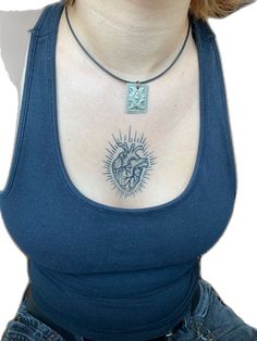 a woman wearing a blue tank top with a heart tattoo on her chest