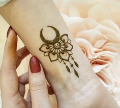 a woman's hand with a henna tattoo on her left wrist and the moon in the background