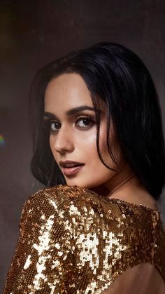 a woman with dark hair wearing gold sequins