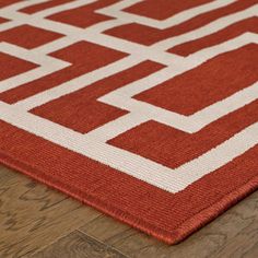 an orange and white rug on top of a wooden floor next to a wood floor