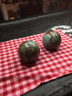 two metal balls sitting on top of a red and white checkered table cloth