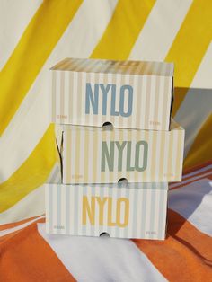 two boxes sitting on top of an orange and white striped tablecloth with the word nylo printed on them