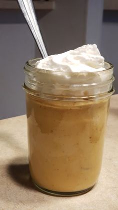 a jar filled with whipped cream sitting on top of a counter next to a spoon