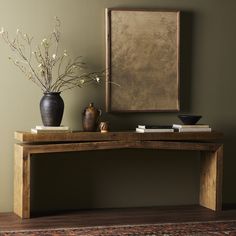 a wooden table with two vases and a painting on the wall in front of it