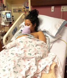 a woman laying in a hospital bed with her face covered by a pink mask and breathing tube