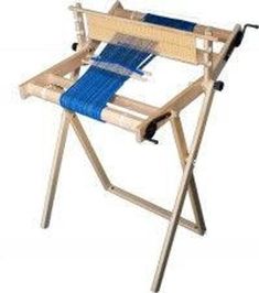 a wooden chair with a blue cloth on the back and seat folded up to it's sides