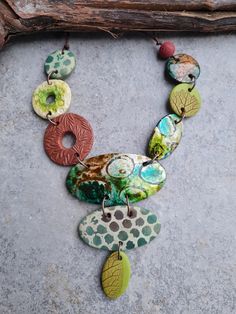 a multi - colored necklace is displayed on a stone surface