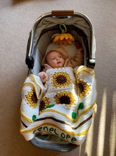 a baby is laying in a stroller with sunflowers on it's blanket