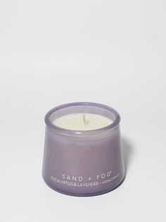 a candle that is sitting on top of a white surface with the words sand fog written in