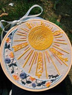 someone is holding up a hand embroidered sun